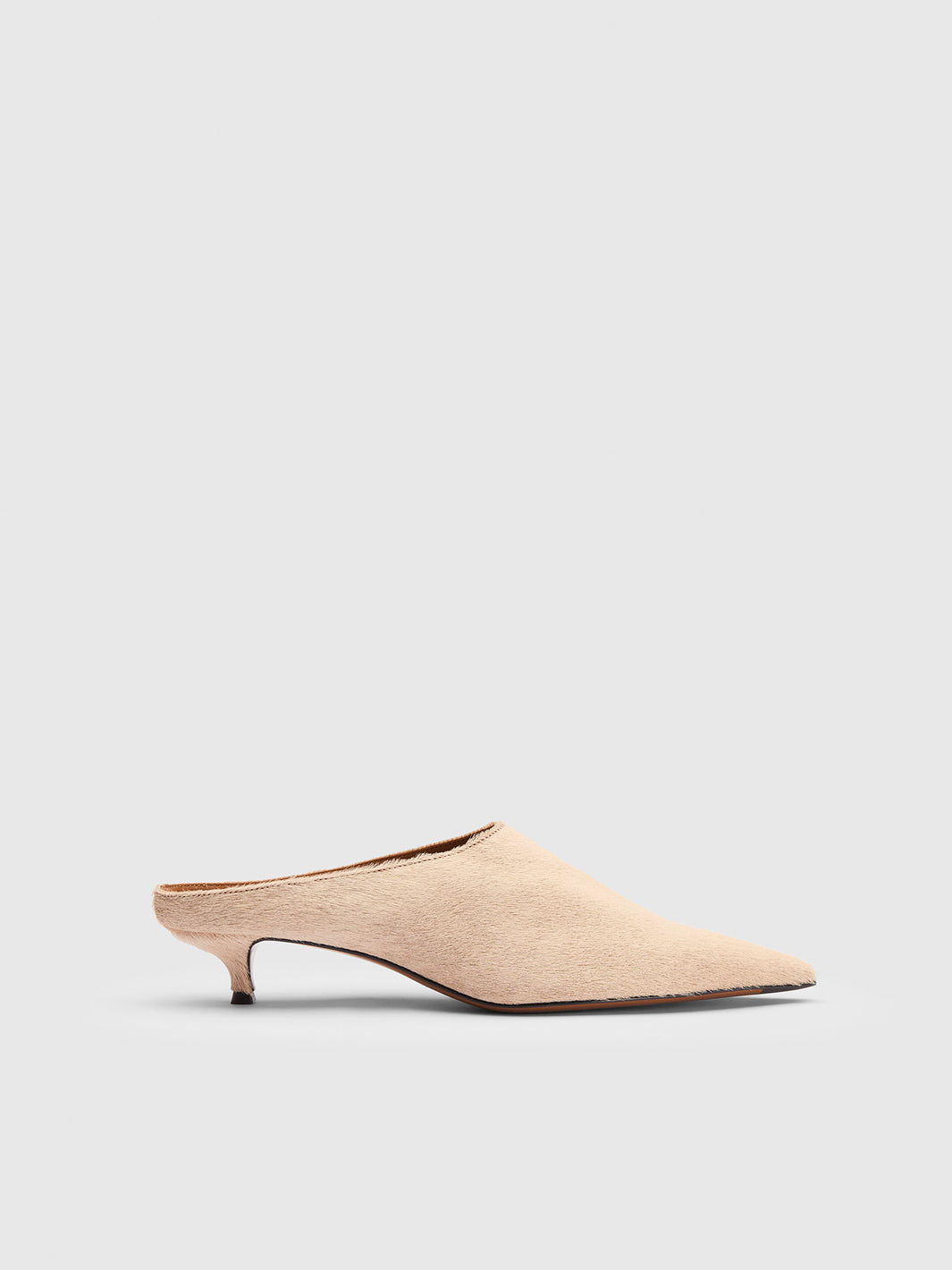 A single light beige pointed-toe mule heel with a kitten heel and open back, shown in profile against a light gray background.