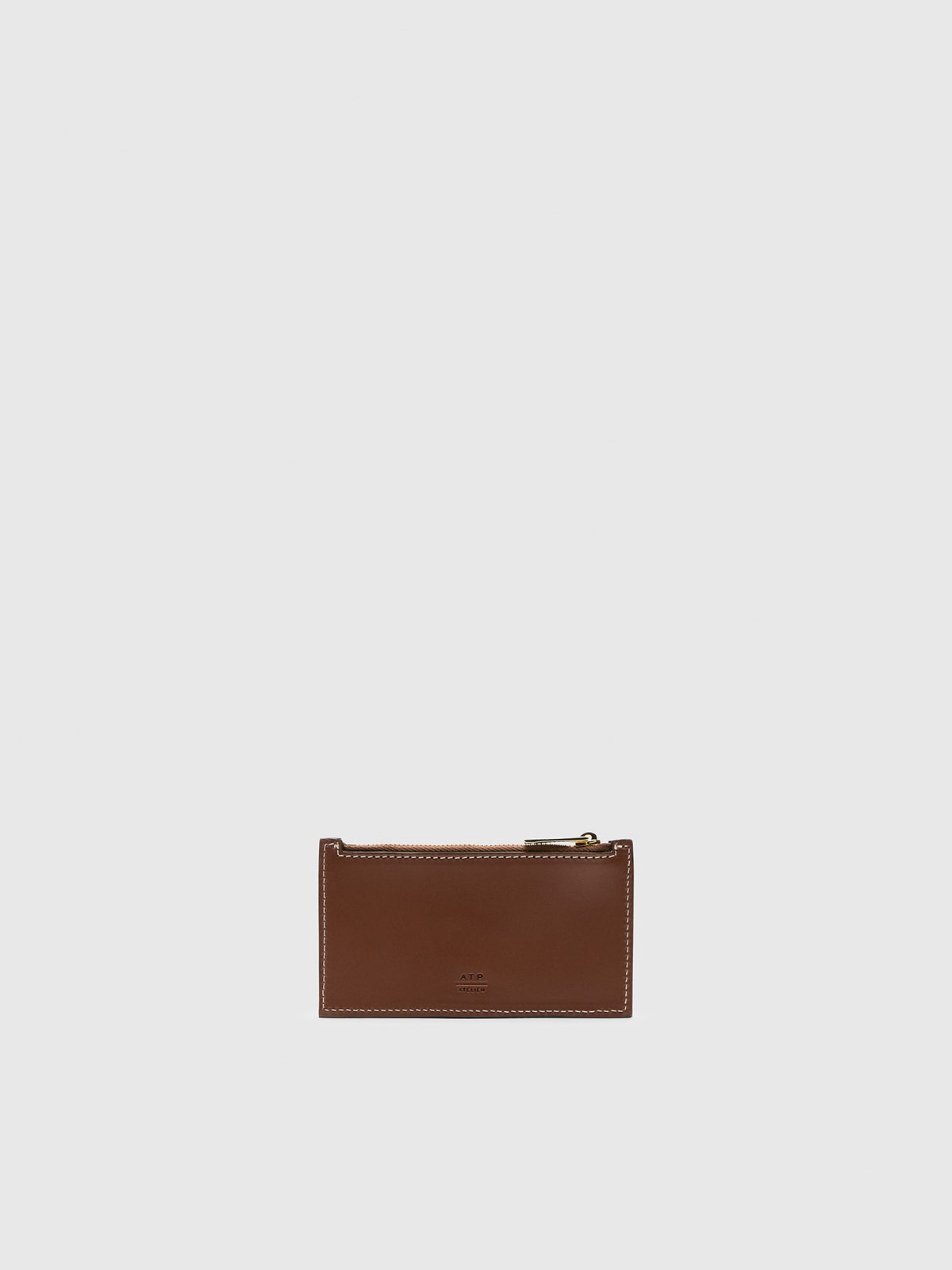 A small brown leather zip pouch with a gold-tone zipper pull, centered against gray background.