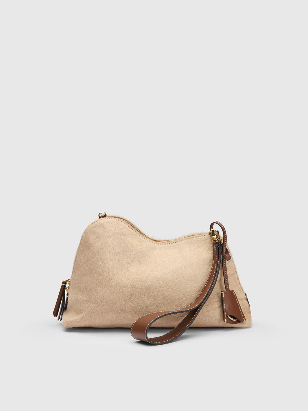 A beige suede shoulder bag with brown leather trim and strap, featuring gold-tone hardware and a zippered top, shown against a light gray background.