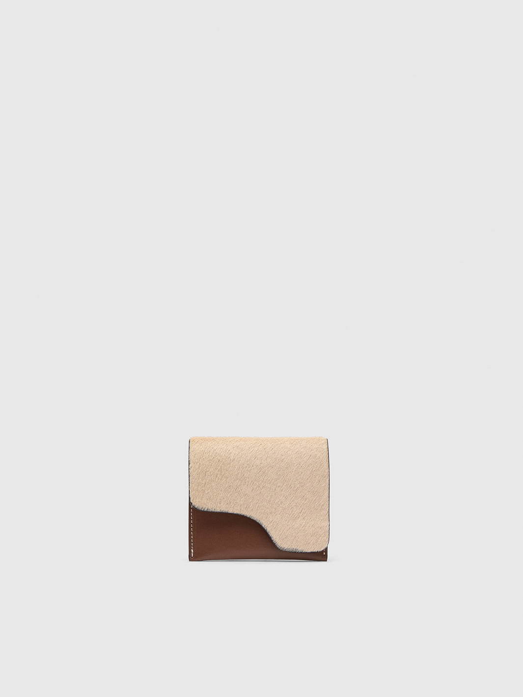 A small bi-fold wallet featuring a hair-on-hide beige flap and a smooth dark brown leather bottom tab, centered on a light gray background.